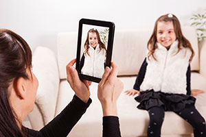 Mother taking picture of daughter on ipad