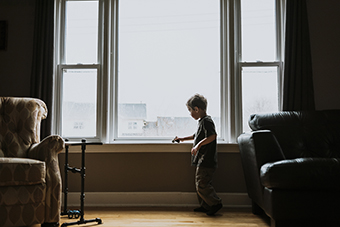 Young boy playing inside by window, outside is foggy/smoky