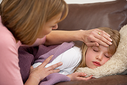 Mom feeling sick daughter's forehead