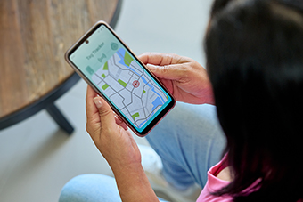Parent holding a phone with a location tracking app on the screen